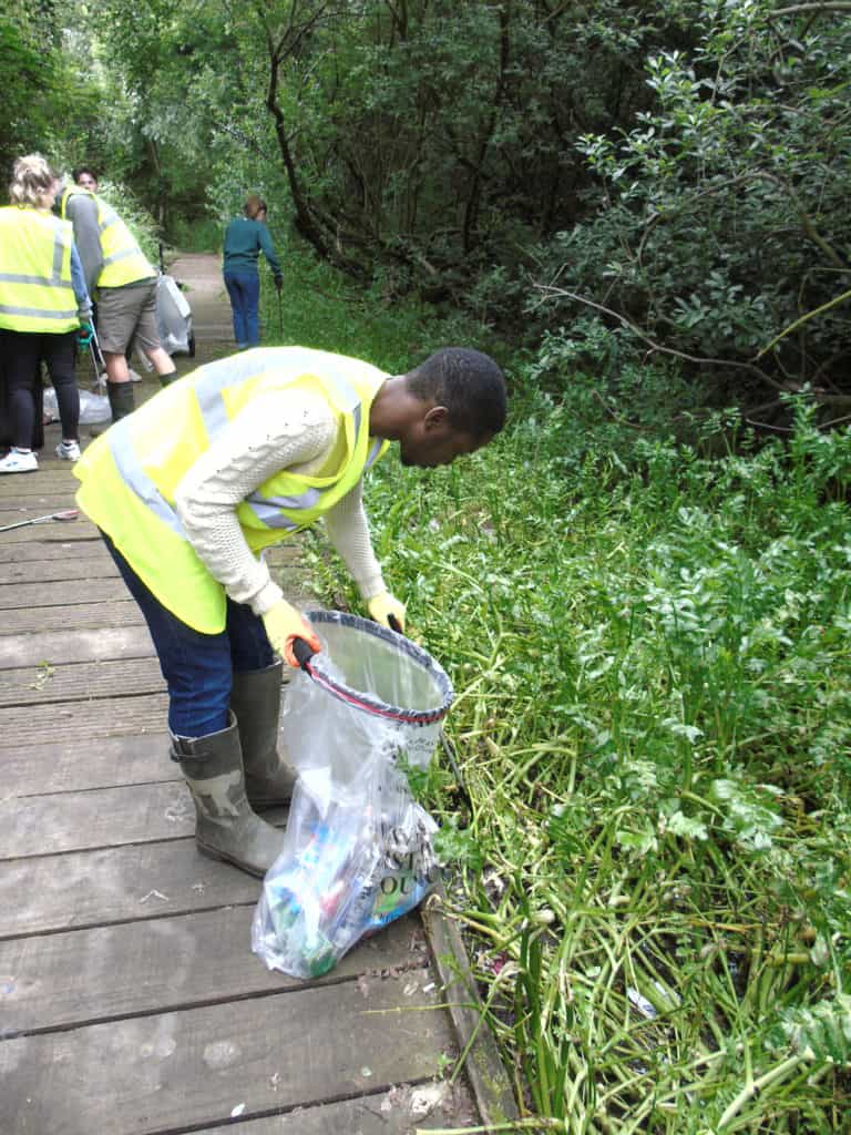Student collecting litter and placing in a rubbish bag